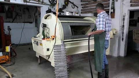 Farmer cleaning a wine press machine after pressing out white wine gapes. Video stock 80023697