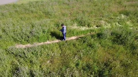 Farmer cutting grass with weed wacker in large field Stock Footage 310016574