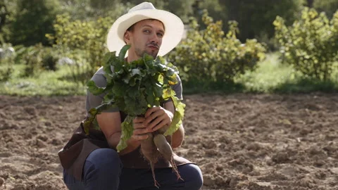 Farmer dances on farm plot with bunch of fresh beets at camera, slow motion. Video stock 246370593