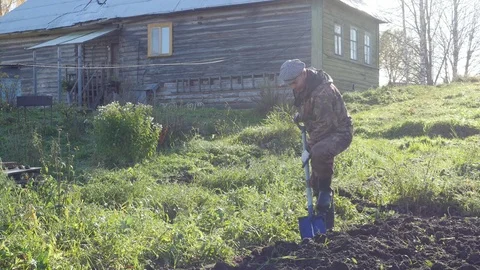 Farmer digging ground in front of his village house, 4k footage Video stock 81428753