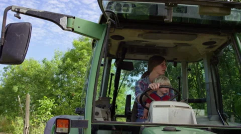 Farmer driving her tractor with son on board Stock Footage 63018670