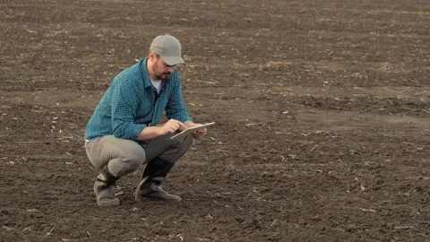 Farmer enters data for report on soil condition into tablet. Man agronomist Video stock 169485992