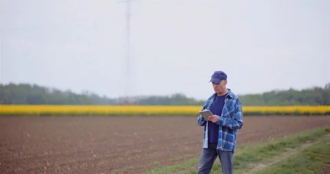 Farmer Examining Agricultural Field While Working on Digital Tablet Computer at Stock-Footage 129632494