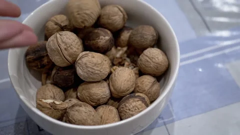 Farmer Hands Putting Walnuts in a Bowl with Collected Nuts on the Table Stock Footage 229471545