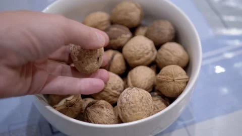 Farmer Hands Putting Walnuts in a Bowl with Collected Nuts on the Table Stock Footage 229788094