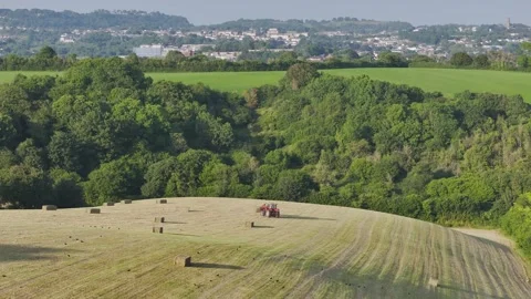 Farmer harvests hay with a tractor in the fields of Devon, Torquay, England Stockbeeldmateriaal 311706533