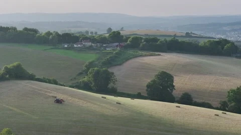 Farmer harvests hay with a tractor in the fields of Devon, Torquay, England Видео 311782383