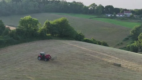 Farmer harvests hay with a tractor in the fields of Devon, Torquay, England Видео 311782439