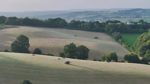 Farmer harvests hay with a tractor in the fields of Devon, Torquay, England Видео 311782451
