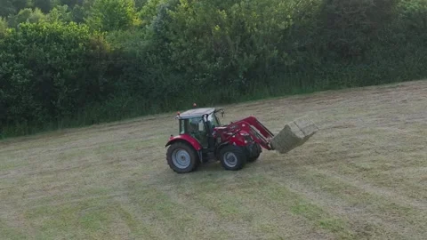 Farmer harvests hay with a tractor in the fields of Devon, Torquay, England Видео 311782488