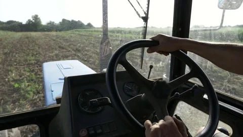 Farmer in hat, sits inside in the tractor cabin, rides on the field with plow. Stock Footage 78363148