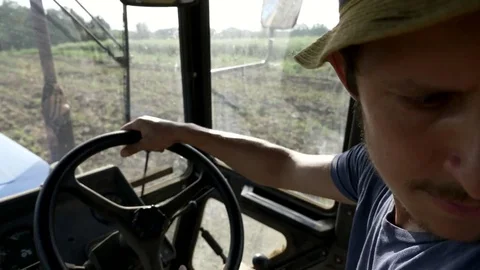 Farmer in hat, sits inside in the tractor cabin, rides on the field with plow. Stock Footage 78363850