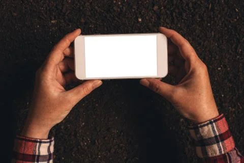 Farmer holding blank screen mobile phone over soil ground Stock Photos