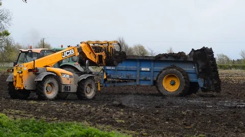 Farmer loading muck spreading machine working in field yorkshire united kingdom Stock Footage 76900397