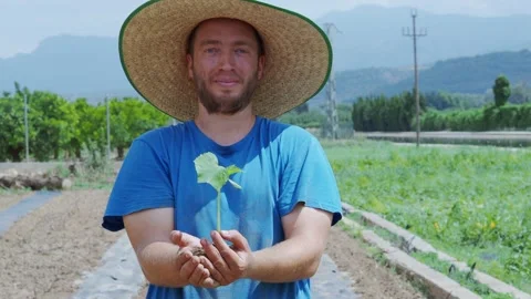 Farmer man looking at camera with a plant in his hands. Sustainable agriculture Stock Footage 231681970