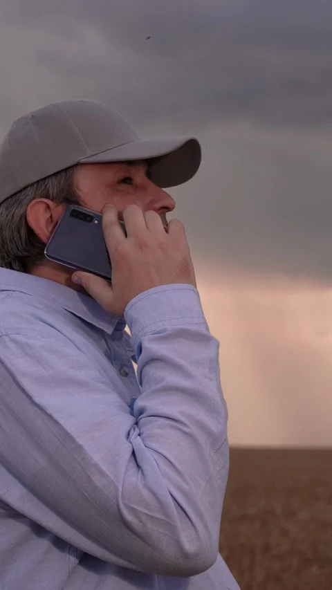 Farmer man in wheat field talking on mobile phone. Businessman talking on Stock Footage 297957770