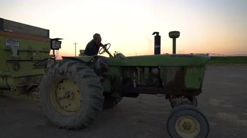 Farmer Mounts Old John Deer Green Tractor at Sunrise Stock Footage 140214566