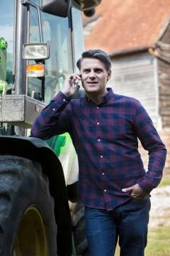 Farmer Next To Tractor Talking On Mobile Phone Stock Photos