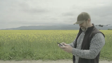 Farmer piloting drone for side tracking shot, ungraded flat color profile Stock Footage 336279222