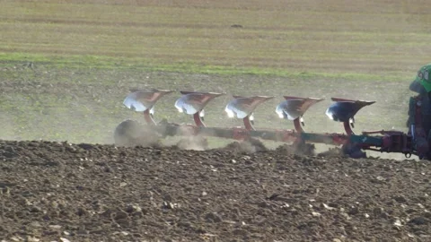 Farmer Ploughing Soil using Tractor with Mouldboard Plough on Sunny Day Stock Footage 141657953
