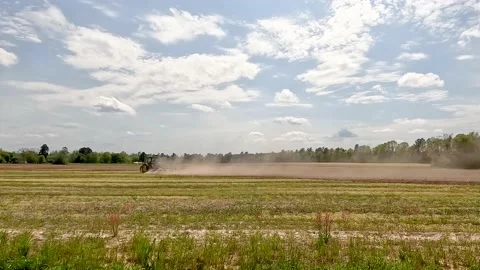 A farmer plowing a field in a John Deere tractor in rural Georgia  cloudy sky Stock Footage 179958870
