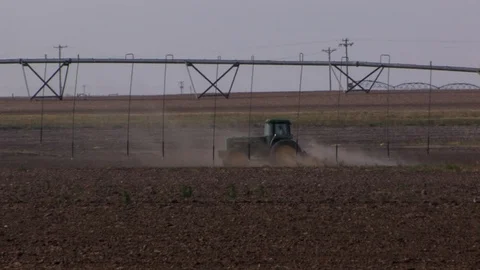 Farmer plows a dry field under a center pivot that's not turned on. Stock Footage 88747083