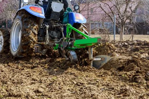 Farmer plows the field. Small tractor with a plow in the field. Cultivation. Stock Photos