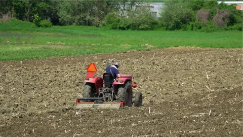 A farmer plows a field with a tractor. Vídeos de archivo 106635598