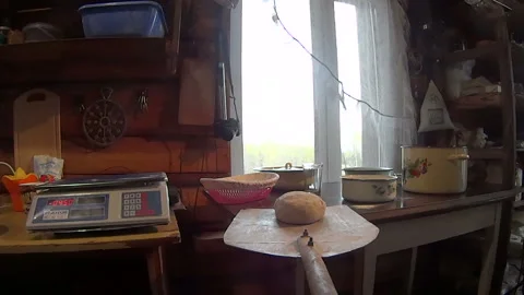 A farmer puts bread in a hot Russian oven on a wooden shovel Stock Footage 85778363