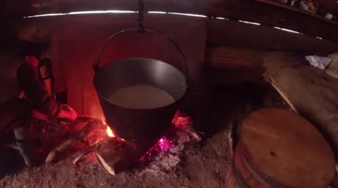 Farmer puts wood on the fire under the pot in a wooden house Stock Footage 43224273