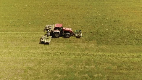 Farmer on a red tractor with a combined mounted mower with disc rotary knives Stock Footage 119643772