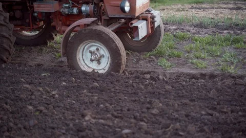 A farmer on a red tractor plows the land in his small plot. Work for farming Stock Footage 108909165