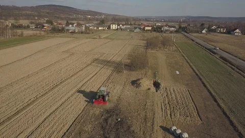 A farmer on a red tractor with a seeder sows grain in plowed land. Stock Footage 104215467