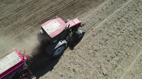 Farmer on a red tractor with a seeder sows grain in plowed land in a private 스톡 동영상 237911359