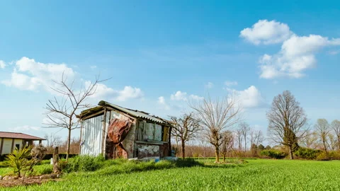 Farmer shack against spring blue sky with white clouds moving, timelapse Stock Footage 151455904