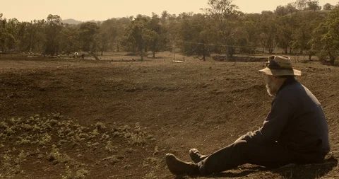 Farmer sitting on empty dam wall on drought stricken farm looking sad Stock Footage 122356223
