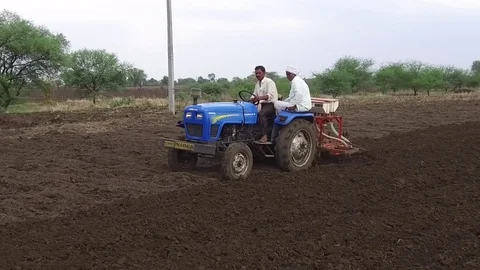 Farmer sowing seeds with automatic seed cum fertilizer drill machine Stock Footage 77572703