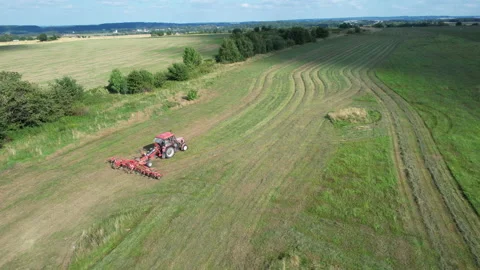 The farmer speeds up the drying of the hay by moving the harvested hay with the Stock Footage 205575223