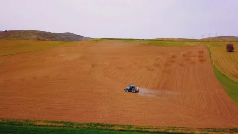 Farmer is spraying a freshly plowed field with his tractor aerial drone view Stock Footage 153607059