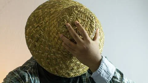 Farmer in straw hat facing downward with face hidden, close-up portrait on .. Stock Photos