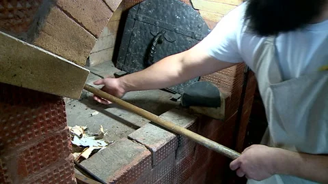 Farmer takes rye bread from the Russian oven on a wooden shovel Stock Footage 85778423