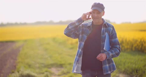 Farmer Talking on Mobile Phone While Working in a Field Agriculture Stock Footage 147698683
