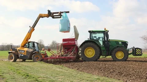 Farmer with a telehandler loading seeds into a seeder driller. UK Stock Footage 150867113