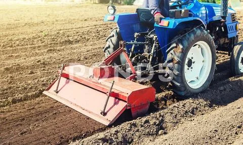 Farmer on a tractor cultivates land after harvesting. Development of ...