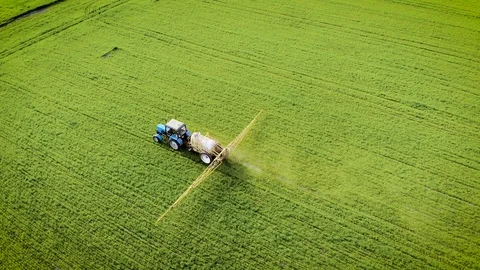 Farmer on tractor finished spraying wheat field and stopped at edge of crops Stock Footage 107941540