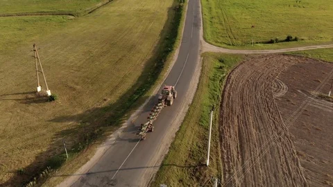 Farmer on a tractor with a plow in a transport position rides on a narrow Stock Footage 119628005