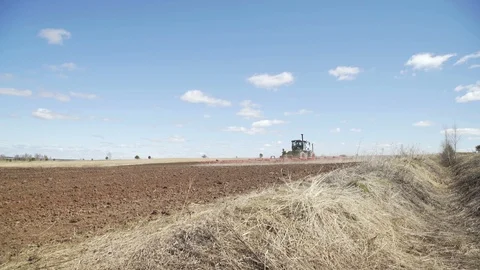 Farmer in tractor preparing land with seedbed cultivator in farmlands. Farmers Stock Footage 106244946