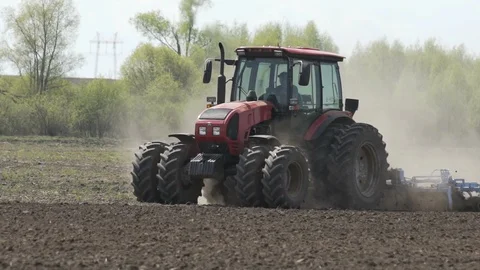 Farmer in tractor preparing land with seedbed cultivator in farmlands. Farmers Stock Footage 106257226