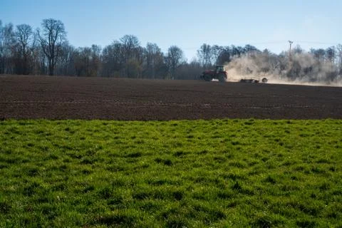 Farmer in tractor preparing land with seedbed cultivator, morning sun Stock Photos