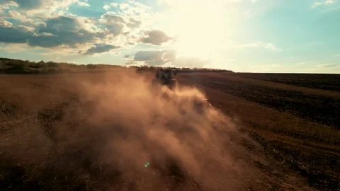 A farmer on a tractor with a seeder sows grain in plowed land in a private field Видео 229417368